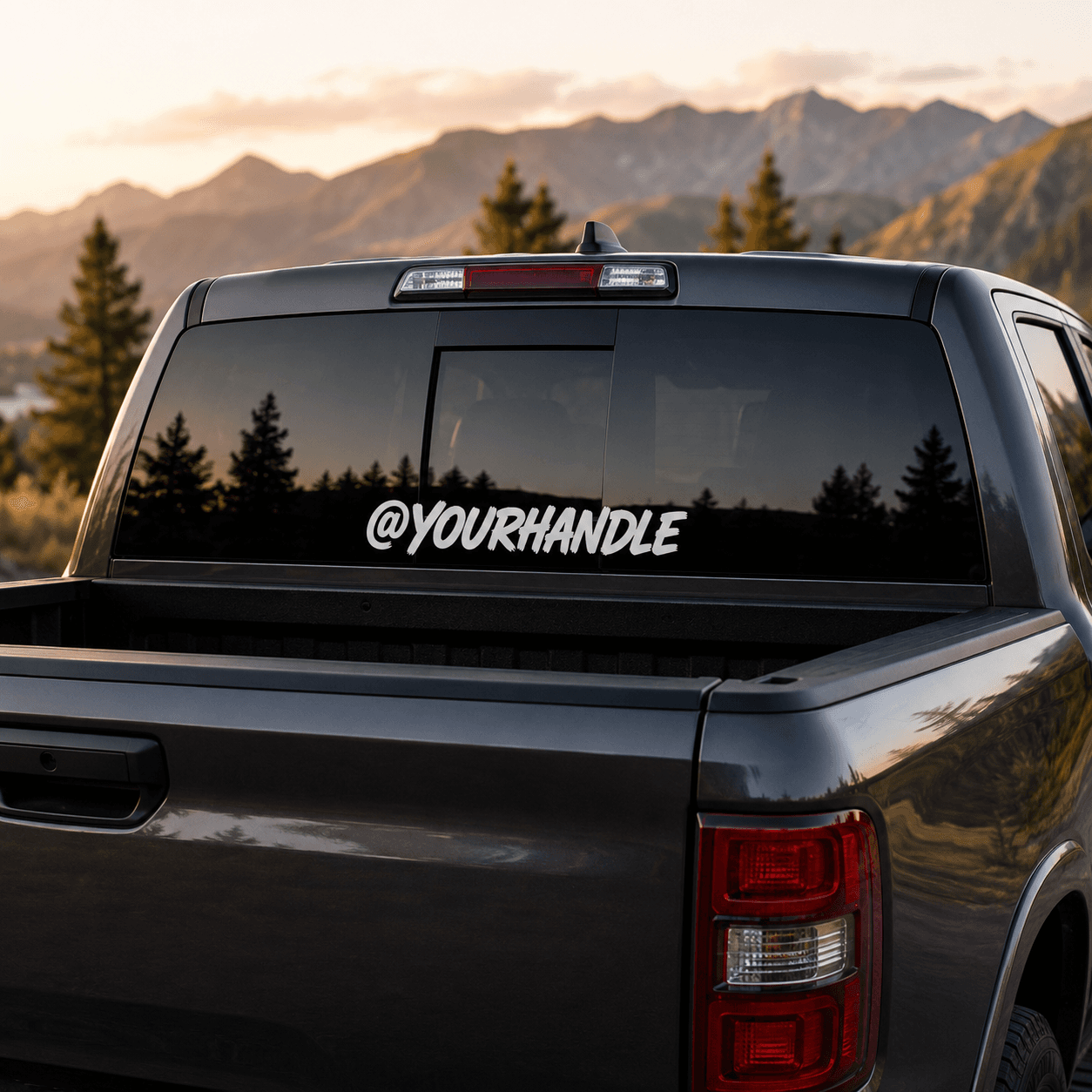 Custom white social handle decal on a dark pickup truck rear window